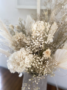 Le bouquet Léonie est magnifique bouquet blanc en fleurs séchées et stabilisées. Il est composée de babalas, de pampa de tête d'hortensias de gypsophiles blanc et de pavots.  Une composition importante d'une hauteur de 75 cm et 45cm de largeur.  Ce bouquet a une grande présence !