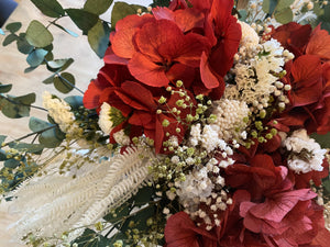Bouquet Amour est notre bouquet pour les amoureux qui veulent de la couleur. Il est composé autour d'un trio de hortensias rouges éternelles sur une base de statices et gypsophile rouge, de diosmi crème, d'une touche de broom vert,  et d'un feuillage d'eucalyptus.   Amour saura mettre de l'amour sur votre console de l'entrée, avec sa douce odeur d'eucalytus, il ne demande aucun entretien, juste un joli vase idéalement rond hauteur 19/20 cm !